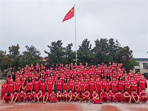 暖心校服润童心  红色薪火永相传   ——武冈市湾头桥镇九年制学校学子身着新装国旗下合影